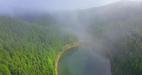 Wall Mural - Flying between fog with a Magical view to the Lake of Empadadas in Sete Cidades, landscape view of the lake on a cloudy day. São Miguel island in the Azores.