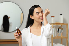 Young Woman Smelling Essential Oil On Wrist Indoors