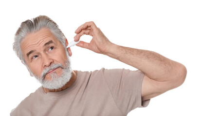 Senior man using ear drops on white background