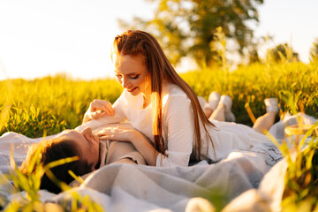 Wall Mural - portrait of happy young man with redhead smiling woman lying down on fresh beautiful field with gree