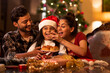 © IndiaPix - Mother feeding cupcakes to her daughter on the occasion of Christmas while father holding plate