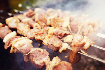 Wall Mural - Selective focus. Cooking barbecue on the mangal in nature. Grilled tasty meet cooking on the party. Traditional Russian shashlik on a barbecue skewer on sunny forest.