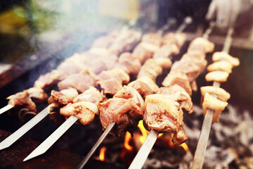 Wall Mural - Selective focus. Cooking barbecue on the mangal in nature. Grilled tasty meet cooking on the party. Traditional Russian shashlik on a barbecue skewer on sunny forest.