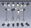© WinWin - Realistic spotlights. Lamp on tripod stand, photo studio or stage light equipment. Spotlight with light beam glow effect vector set