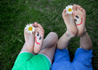 Leinwandbild Motiv funny smiling faces painted on bare feet of two children lying on grass. Cheerful childhood. positive atmosphere, hello summer. friendship day. surprise for mom on mother's day. selective focus