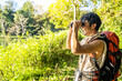 © TeTe Song - Young travel man relax and enjoy in the Woods Looking Out Through Binoculars at a beautiful landscape, Hiking in the mountains.
