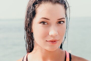 Woman sea sup. Close up portrait of beautiful young caucasian woman with black hair and freckles looking at camera and smiling. Cute woman portrait in a pink bikini posing on sup board in the sea