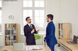 © Studio Romantic - Business people working in the office. Two young men in suits talking while standing by a desk in a modern office interior. Serious manager giving some instructions to a new employee