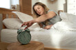 © gpointstudio - Close up of alarm clock with woman's hand from bed