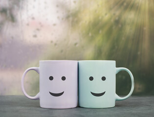Wall Mural - Happy, similing face, mug couple on a window sill cuddle, cup of coffee on a rainy day, support, relationship and friendship concept
