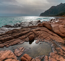 Coccorocci Beach With Tidal Pools In The Red Stone And A View Of The Rugged Coast Of Sardinia