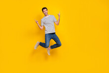 Full Length Photo Of Cheerful Cool Guy Dressed Striped T-shirt Showing Hard Rock Signs Jumping High Isolated Yellow Color Background