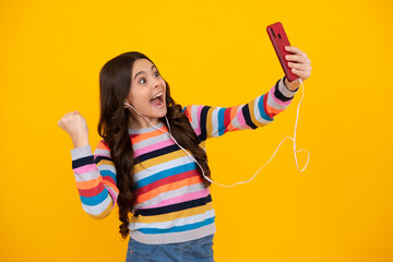 Canvas Print - Kids selfie. Close-up portrait of cute teen girl using mobile phone, cell web app, isolated over bright vivid vibrant yellow color background. Happy teenager, positive and smiling.