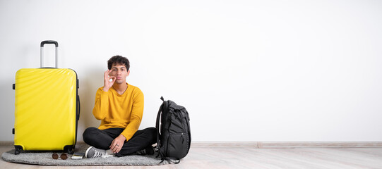 Wall Mural - Arabic traveler man with suitcase making gesture with hand, zipping lips, promising to keep secret, isolated on white background.