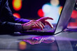 © Lustre Art Group  - Cropped image of male hands of business man typing on laptop keyboard at evening time. Cool colored neon hue lights in office space.