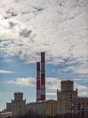 Poster - CHP in the city. Smoke rises into the sky from the heat pipes of the power plant. Pipe of combined heat and power plant CHP or cogeneration against background of multi-storey residential buildings