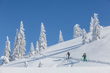 Majestic mountain landscape on a cold winter morning with two hikers with backpacks