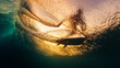 Surfer rides the wave and grabs the water surface. Underwater through the wave view of the surfer riding the wave and touching the water