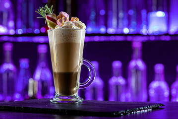 Cocktail layered baileys irish cream iced coffee on bar counter in a restaurant, pub. Drink with liqueur. Fresh prepared alcoholic cooler beverage at nightclub. Showcases with bottles, dark background