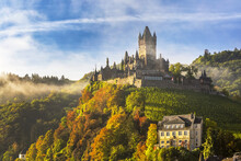 Large Medieval Castle On A Colourful Treed Hillside With Fog, Blue Sky And Cloud; Cochem, Germany