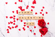 Valentines day postcard. Romantic  layout. Wooden latters, red roses flowers and little hearts on  white marble background.  Top view.