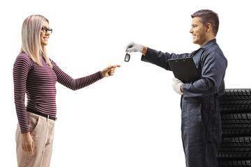 Poster - Auto mechanic with a pile of tires giving car keys to a woman