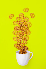 Wall Mural - A cup with effuse pretzels on green background, flat lay, conceptual minimalism.