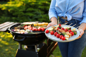 Wall Mural - Woman with delicious grilled vegetables near barbecue grill outdoors, closeup. Space for text