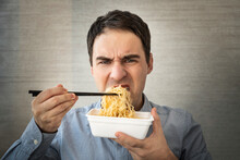 Man Eating Instant Noodles While Working With In Office. Lunch At The Office. Tasteless Junk Food