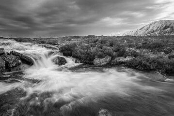 Wall Mural - Black and white Majestic Winter landscape image of River Etive in foreground with iconic snowcapped Stob Dearg Buachaille Etive Mor mountain in the background