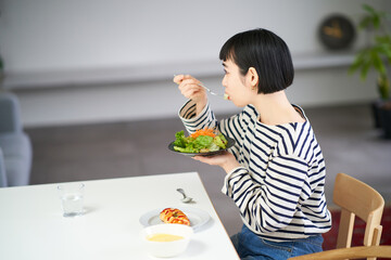 Wall Mural - 家のダイニングで食事をする女性 