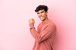 © luismolinero - Young Argentinian man isolated on pink background celebrating a victory