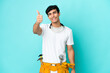 © luismolinero - Young electrician Argentinian man isolated on blue background with thumbs up because something good has happened