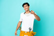 © luismolinero - Young electrician Argentinian man isolated on blue background pointing front with happy expression