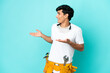 © luismolinero - Young electrician Argentinian man isolated on blue background with surprise expression while looking side