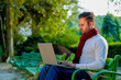 © PRASANNAPIX - Young indian man in warm wear and working on laptop at park