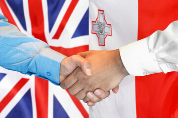 Wall Mural - Business handshake on background of two flags. Men handshake on background of UK flag and flag of Malta. Support concept