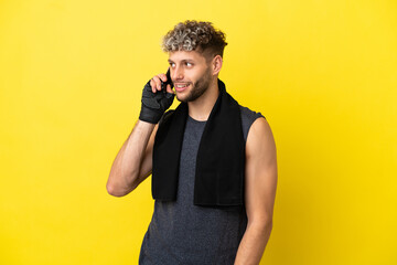 Poster - Sport caucasian man isolated on yellow background keeping a conversation with the mobile phone with someone