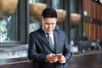 Wall Mural - Asian business man wear suit standing using smartphone