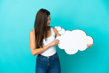 Wall Mural - Young Brazilian woman isolated on blue background holding a thinking speech bubble