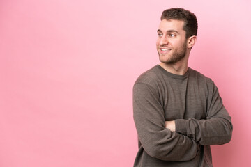 Wall Mural - Young caucasian man isolated on pink background looking to the side and smiling