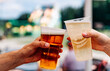 © pavel siamionov - two plastick cup of beer in man and woman hands. Beer clinking outdoor