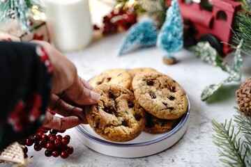 Wall Mural - Hand holding chocolate chip cookie on holiday background, selective focus