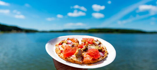 Wall Mural - man holds plate with mini pita pizza in hands. Street food, fast food outdoor