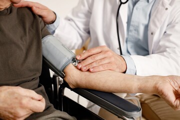 Wall Mural - Cropped photo of doctor's hands measuring of man's arterial pressure