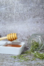 Honey And Herbs From The Woody Stems Of Rosemary, On A Stone Background, Along With A Glass Jar And A Honey Stick.