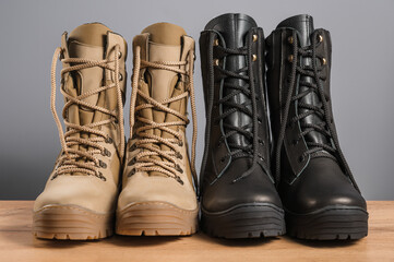 Khaki and black tall military boots on a gray background