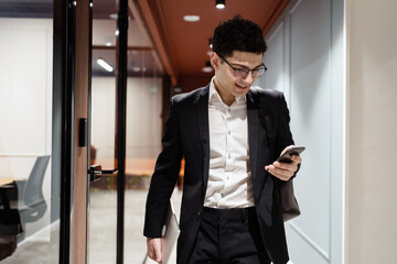 Wall Mural - Phone message a manager with glasses goes to work in the office in a business suit, smiles and thinks about the project.