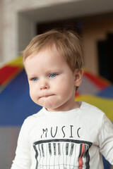 Wall Mural - the little boy purses his lips ridiculously. portrait of a beautiful blue-eyed child.