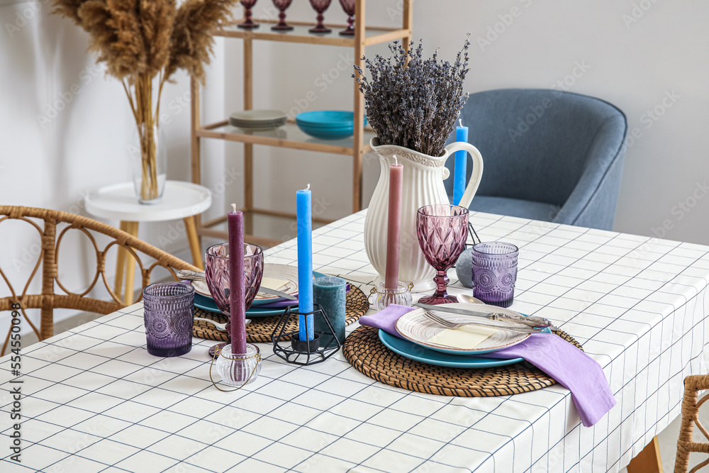 Dinnerware and lavender flowers on served table in light room